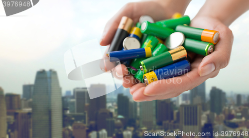 Image of close up of hands holding alkaline batteries heap