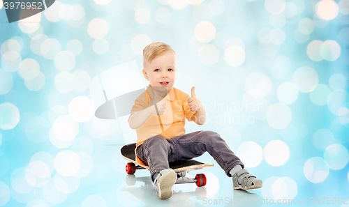 Image of happy little boy on skateboard showing thumbs up