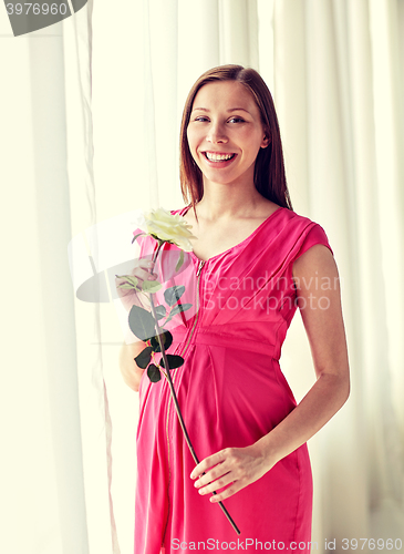 Image of happy pregnant woman with rose flower at home