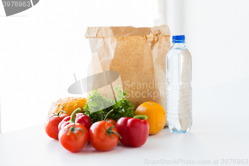 Image of close up of paper bag with vegetables and water