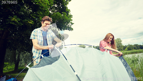 Image of happy couple setting up tent outdoors