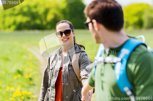 Image of happy couple with backpacks hiking outdoors