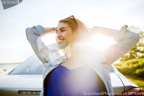 Image of happy teenage girl or young woman near car