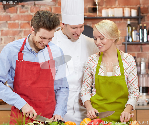 Image of happy couple and male chef cook cooking in kitchen