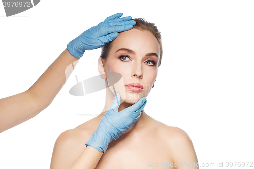 Image of surgeon or beautician hands touching woman face