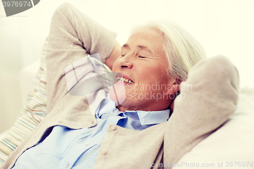 Image of happy senior woman resting on sofa at home