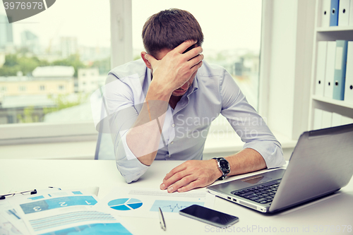 Image of stressed businessman with papers in office