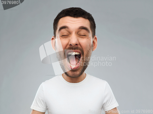 Image of crazy shouting man in t-shirt over gray background