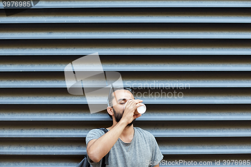 Image of man drinking coffee from paper cup on street