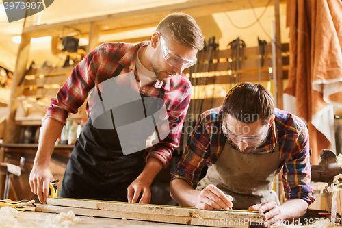 Image of carpenters with ruler and wood plank at workshop