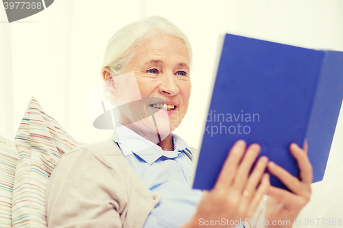 Image of happy smiling senior woman reading book at home