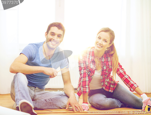 Image of smiling couple measuring wood flooring