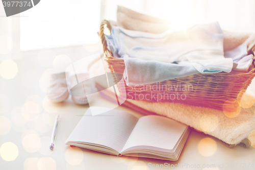 Image of close up of baby clothes for newborn and notebook