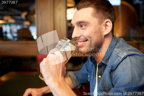 Image of happy man drinking draft beer at bar or pub