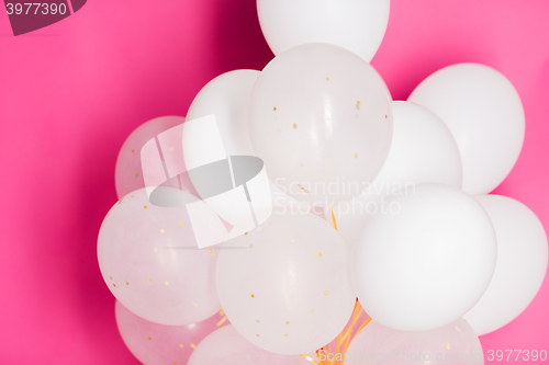Image of close up of white helium balloons over pink