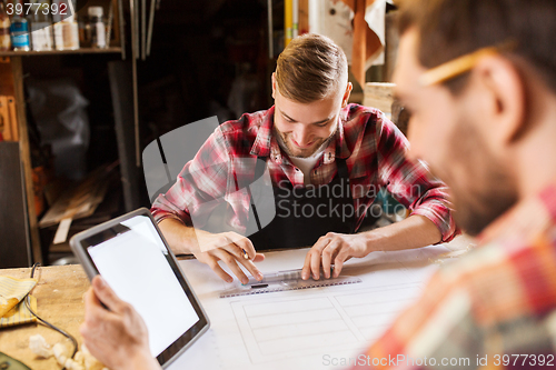 Image of workmen with tablet pc and blueprint at workshop