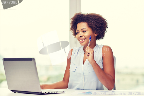 Image of happy african woman with laptop at office