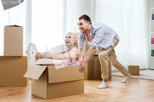 Image of couple with cardboard boxes having fun at new home