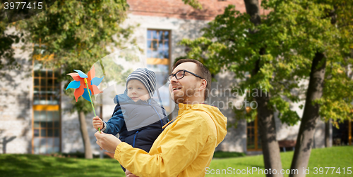 Image of happy father and son with pinwheel toy outdoors