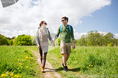 Image of happy couple with backpacks hiking outdoors