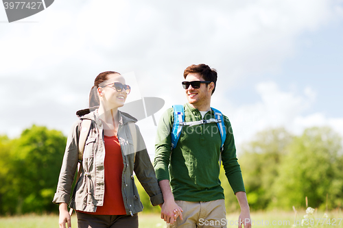 Image of happy couple with backpacks hiking outdoors