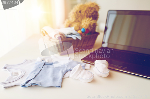 Image of close up of baby clothes, toys and laptop at home