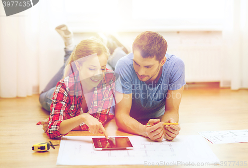 Image of smiling couple looking at tablet pc at home