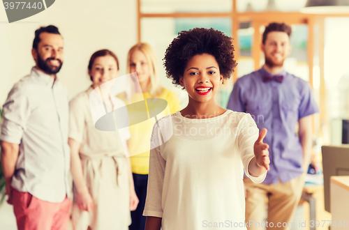 Image of woman making handshake over creative office team