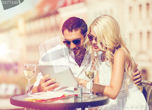 Image of couple looking at tablet pc in cafe