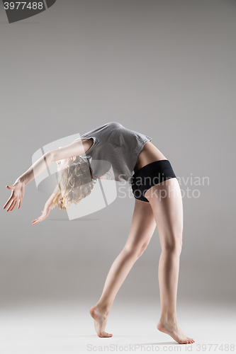 Image of young beautiful woman in grey T-shirt and black shorts dancing