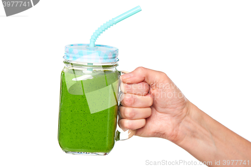 Image of Human hand holding jar tumbler mug with green smoothie
