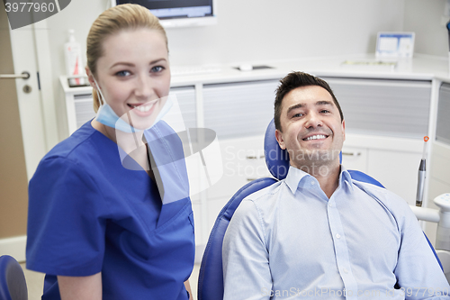 Image of happy female dentist with man patient at clinic