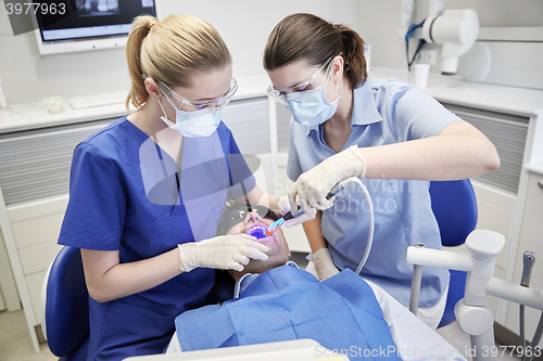 Image of dentists treating male patient teeth at clinic