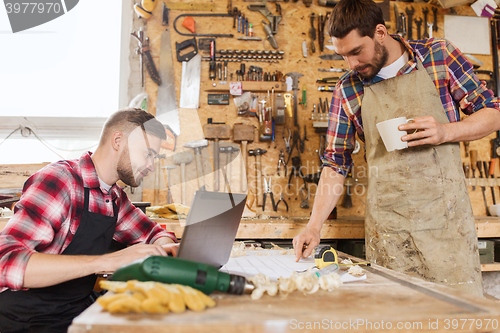 Image of carpenters with laptop and blueprint at workshop