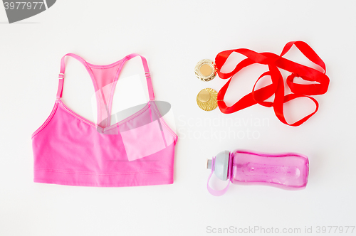 Image of close up of sports top, golden medals and bottle