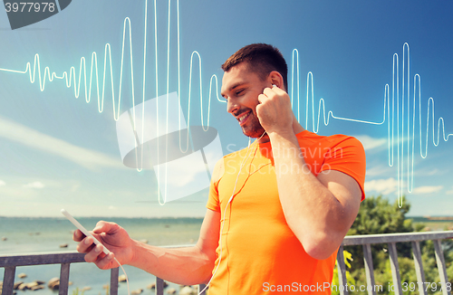 Image of smiling young man with smartphone and earphones