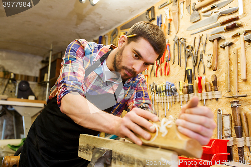 Image of carpenter working with plane and wood at workshop