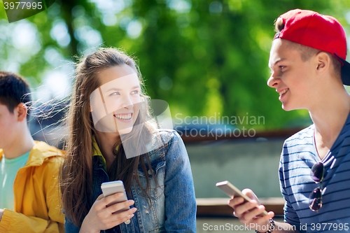 Image of happy teenage friends with smartphones outdoors