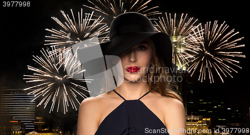 Image of beautiful woman in black hat over night firework