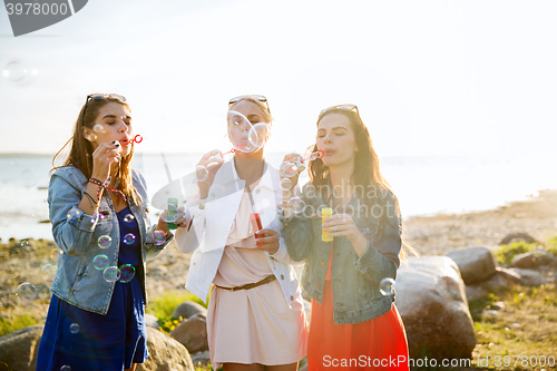 Image of young women or girls blowing bubbles on beach