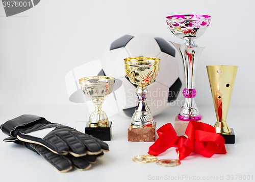 Image of close up of football, gloves, cups and medals