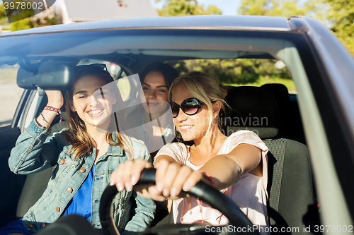 Image of happy teenage girls or young women driving in car
