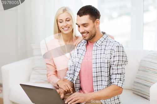 Image of smiling happy couple with laptop computer at home