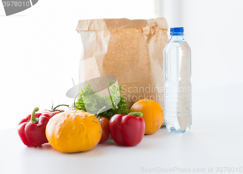 Image of close up of paper bag with vegetables and water