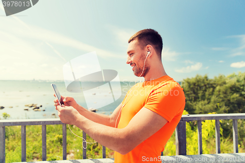 Image of smiling young man with smartphone and earphones