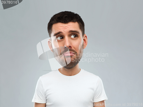 Image of unhappy young man over gray background