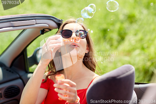 Image of woman blowing bubbles in convertible car