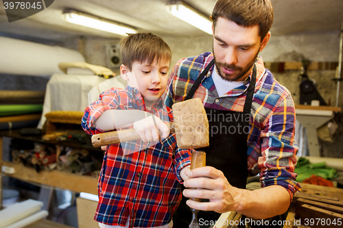 Image of father and son with chisel working at workshop