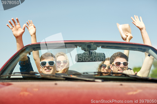 Image of happy friends driving in cabriolet car at country