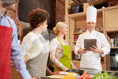 Image of happy friends with tablet pc in kitchen